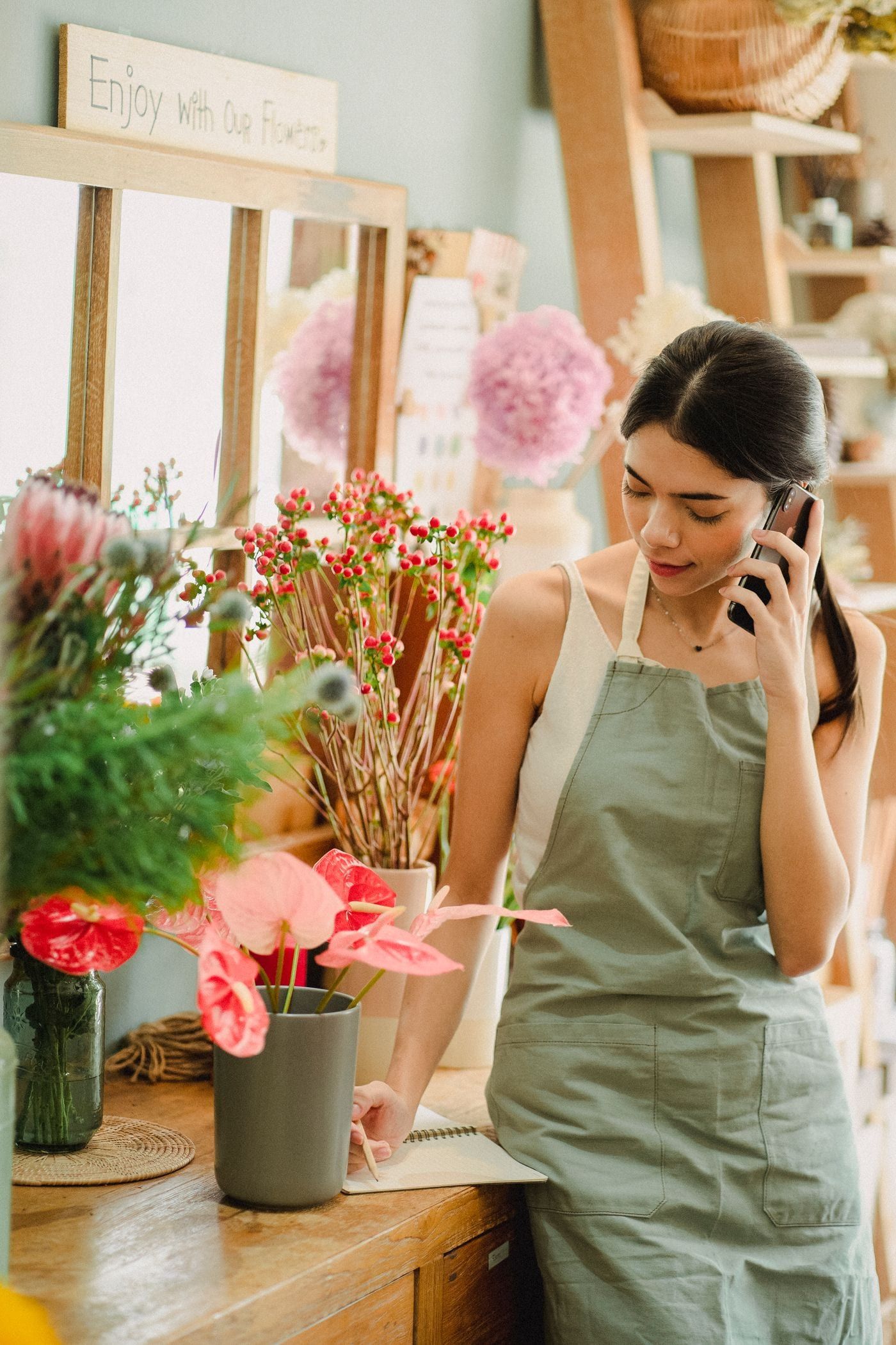 Florista atiende a un cliente por teléfono mientras toma nota