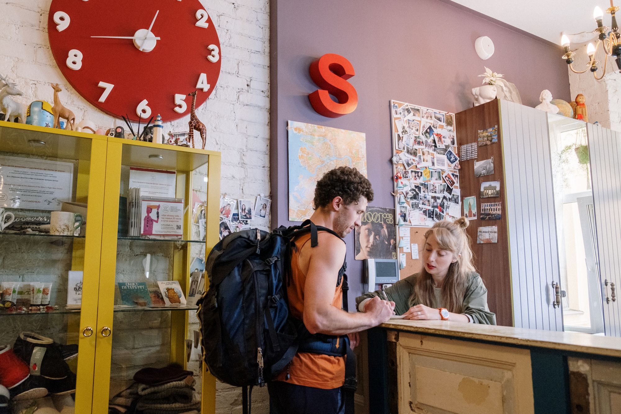 Un viajero con morral hace el check-in en la recepción de un hostal pequeño